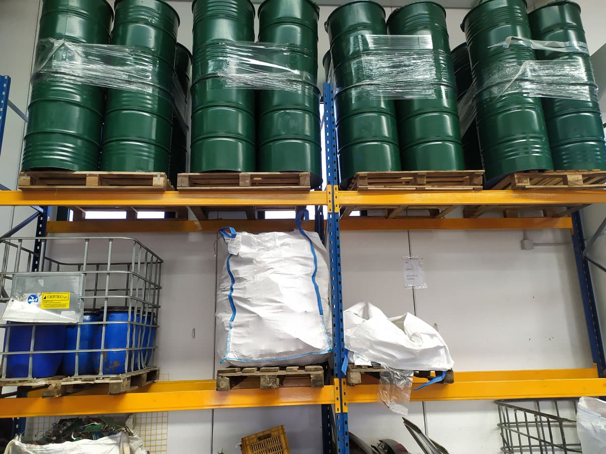 Deposito rifiuti D&D: fusti e big bag stoccati su scaffalature per la raccolta e lo smaltimento